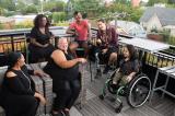 Overhead shot of six disabled people of color at a rooftop deck party.
