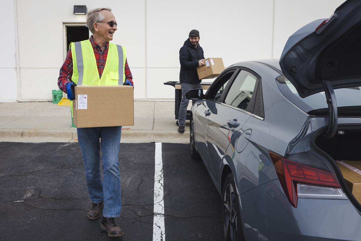 Two volunteers loading a grocery order into a car.  